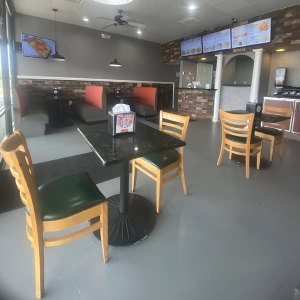 Interior of Southern Style Chicken & Waffle with empty tables, booths, and menu boards on the wall.
