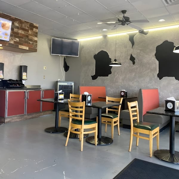 Interior of Southern Style Chicken & Waffle with red booths, wooden chairs, and map-like wall decor.