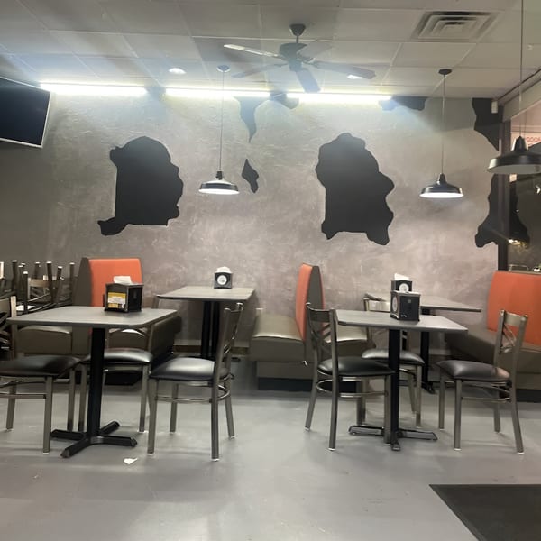 Empty dining room at Southern Style Chicken & Waffle with tables, chairs, booths, and cow-print walls.