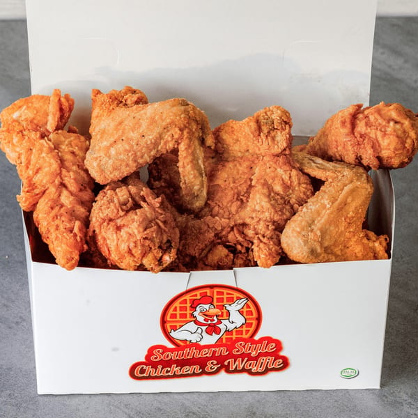 Crispy fried chicken pieces fill a white Southern Style Chicken & Waffle takeout box.
